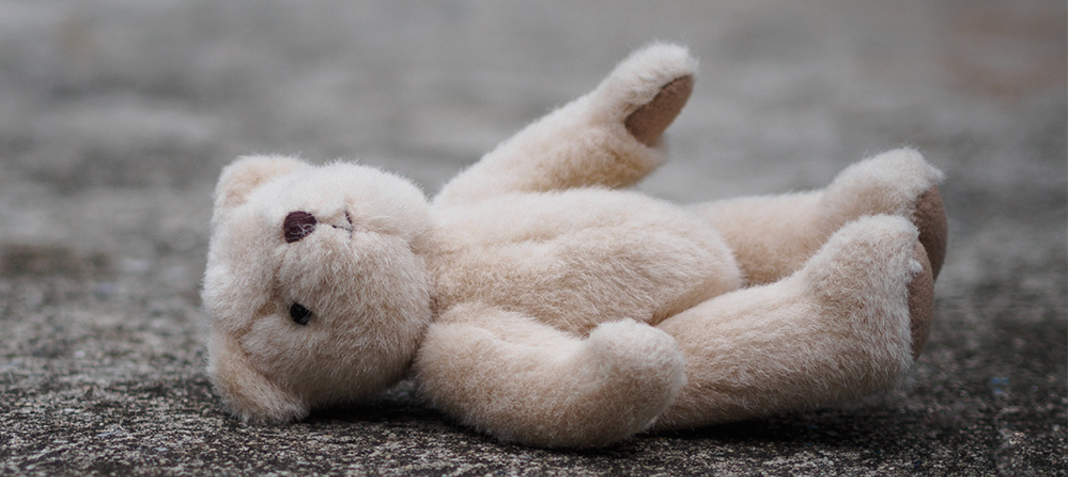 Foto de um urso de pelúcia caído no chão