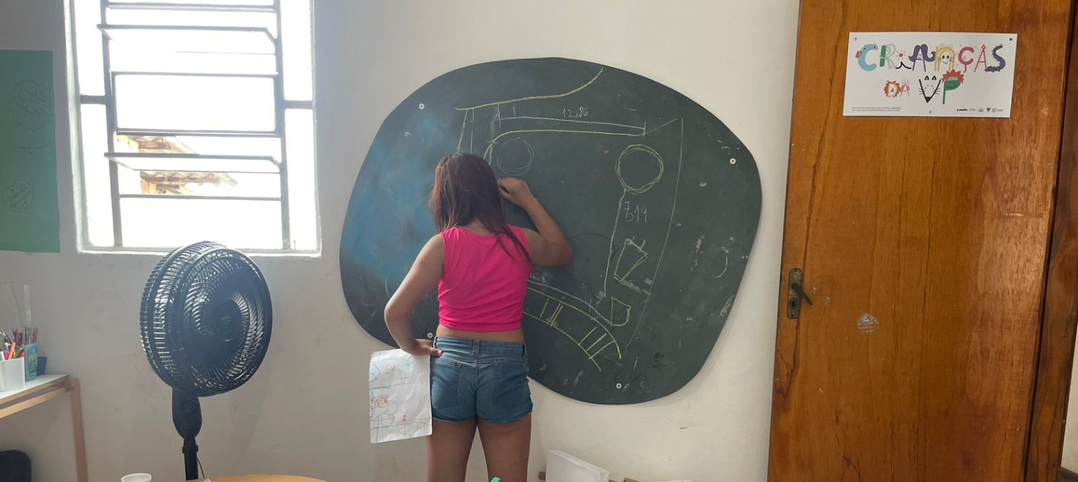 Criança desenhando um mapa de como ficaria a Pracinha da Pedreira
