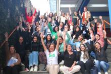 Professoras sentadas levantando os braços