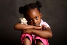 Criança sentada com pelúcia nos braços 