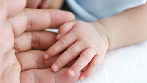 Foto em close de mãe e filho com as mãos dadas