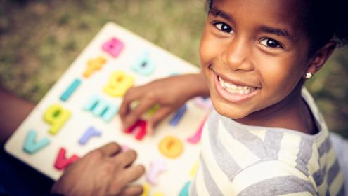 Criança sorrindo com caderno de lição