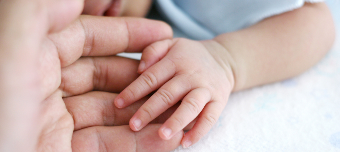 Foto em close de mãe e filho com as mãos dadas